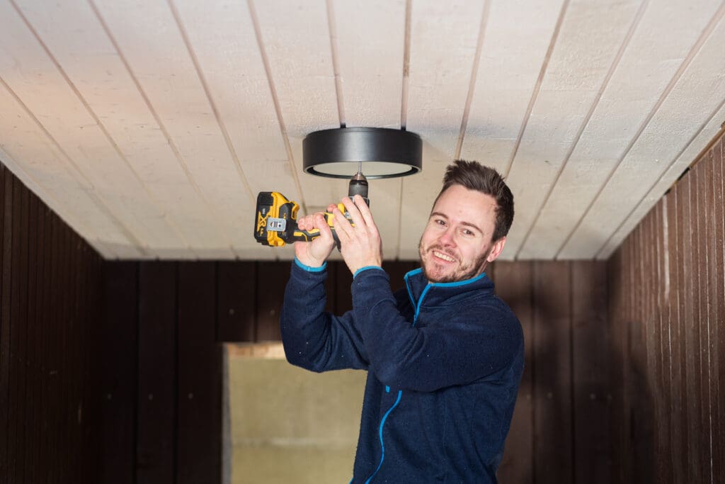 mannlig elektriker monterer en lampe i taket