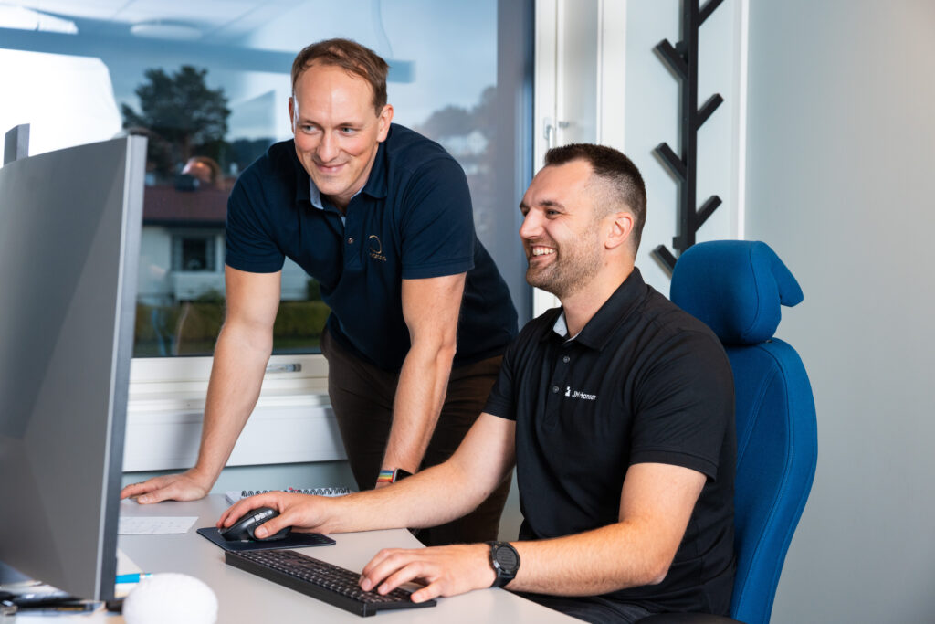 To menn i samtale foran en PC-skjerm